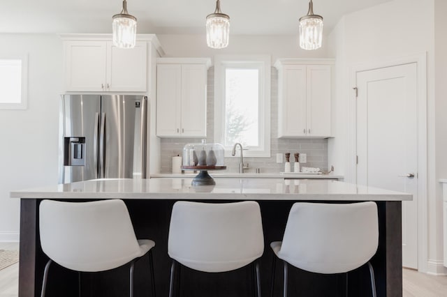 kitchen featuring white cabinets, stainless steel fridge, hanging light fixtures, and a center island