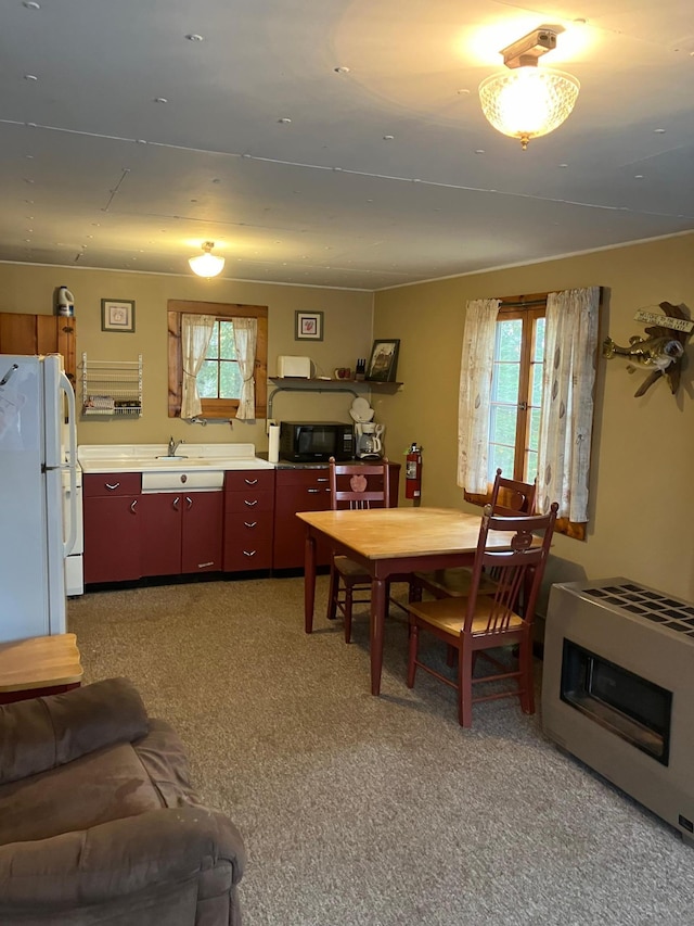 interior space with carpet, white fridge, heating unit, and plenty of natural light