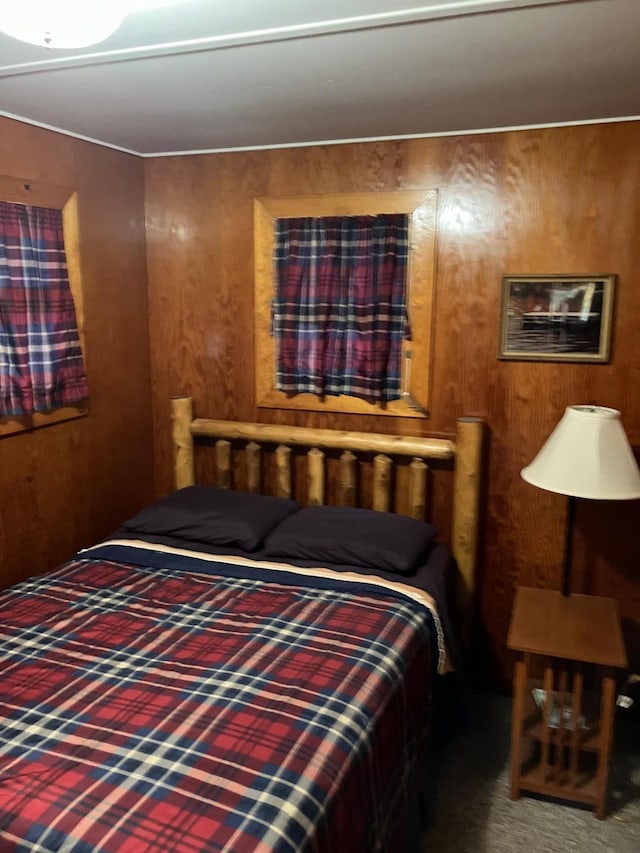 bedroom with wooden walls and dark carpet