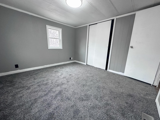 unfurnished bedroom with ornamental molding, dark colored carpet, and a textured ceiling