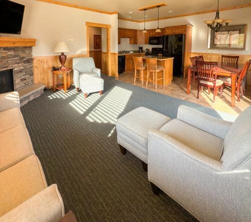 living room featuring crown molding and a stone fireplace