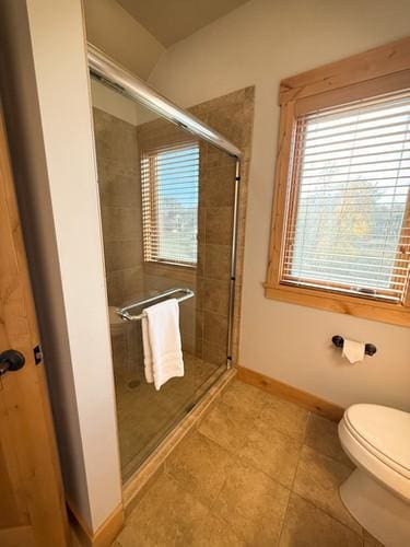 bathroom featuring a shower with door, plenty of natural light, and tile patterned floors