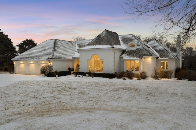 french country home featuring brick siding and an attached garage