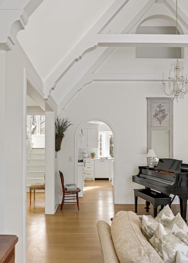 living area featuring a healthy amount of sunlight, light wood finished floors, a chandelier, and arched walkways