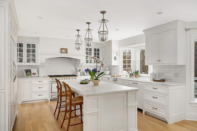 kitchen with range with gas stovetop, a breakfast bar, white cabinets, a kitchen island, and light wood-type flooring