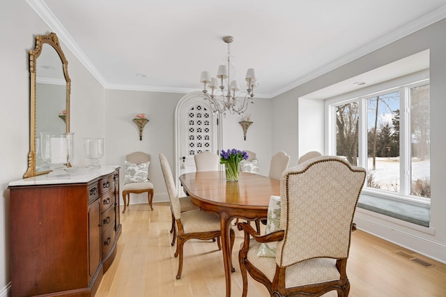 dining area with ornamental molding, a chandelier, visible vents, and light wood finished floors