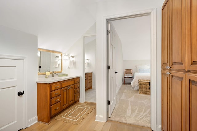 ensuite bathroom with vaulted ceiling, vanity, ensuite bath, and wood finished floors