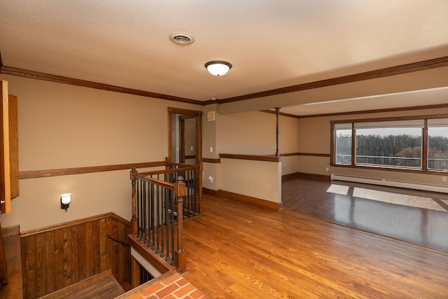 2700 115th St NW, Oronoco, MN 55960 - empty room featuring crown molding, visible vents, baseboard heating, and wood finished floors
