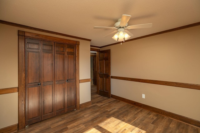 2700 115th St NW, Oronoco, MN 55960 - unfurnished bedroom with a closet, ornamental molding, baseboards, dark wood-type flooring, and a ceiling fan