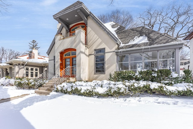 view of front of property featuring a shingled roof, a balcony, and stucco siding