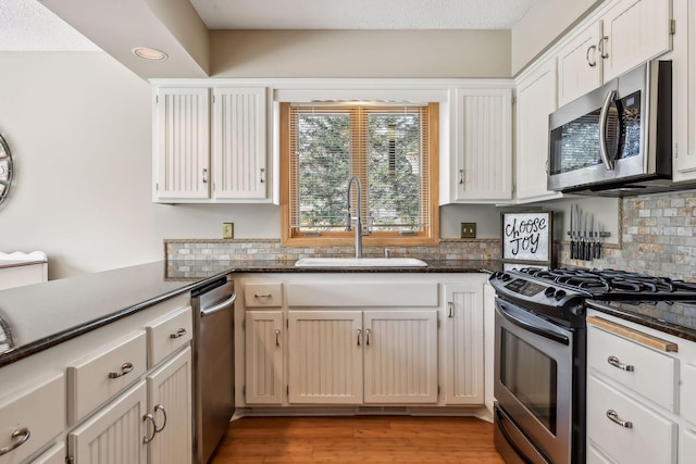 kitchen featuring white cabinetry, sink, light hardwood / wood-style flooring, and appliances with stainless steel finishes