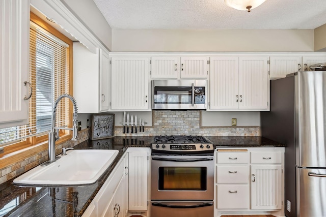 kitchen featuring white cabinets, appliances with stainless steel finishes, a textured ceiling, and sink