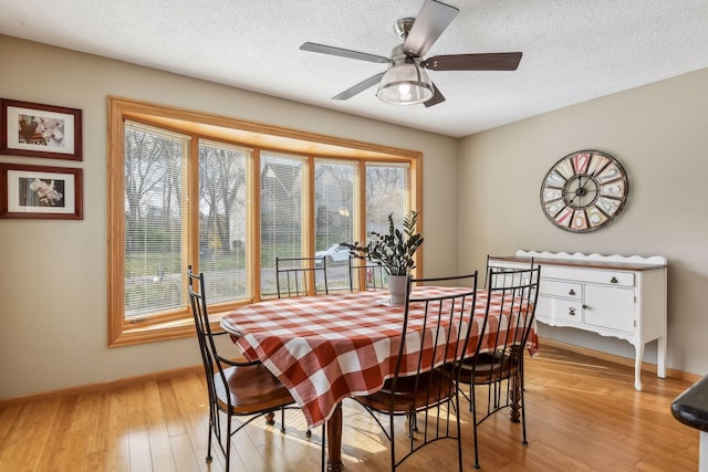 dining space with ceiling fan, light wood-type flooring, and a textured ceiling