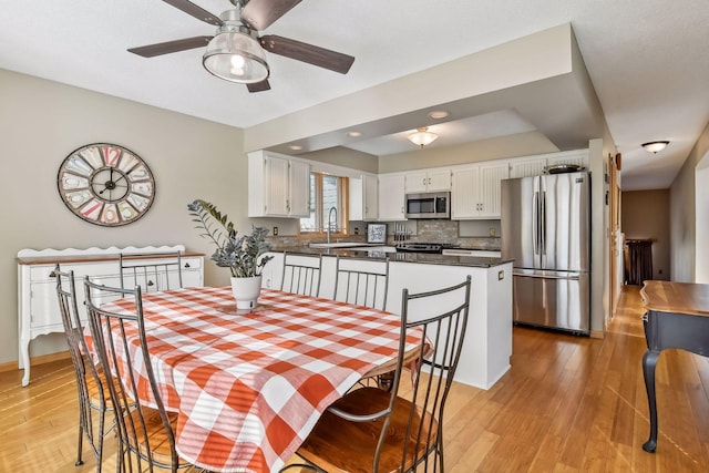 dining area featuring ceiling fan, sink, and light hardwood / wood-style floors