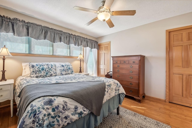 bedroom with ceiling fan, light hardwood / wood-style floors, and a textured ceiling