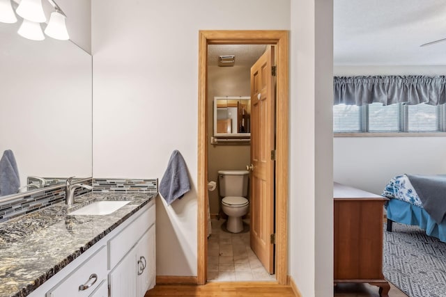 bathroom with vanity, toilet, a textured ceiling, and tasteful backsplash