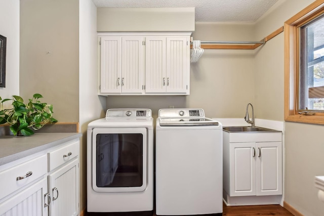 washroom featuring sink, dark wood-type flooring, cabinets, a textured ceiling, and washer and dryer