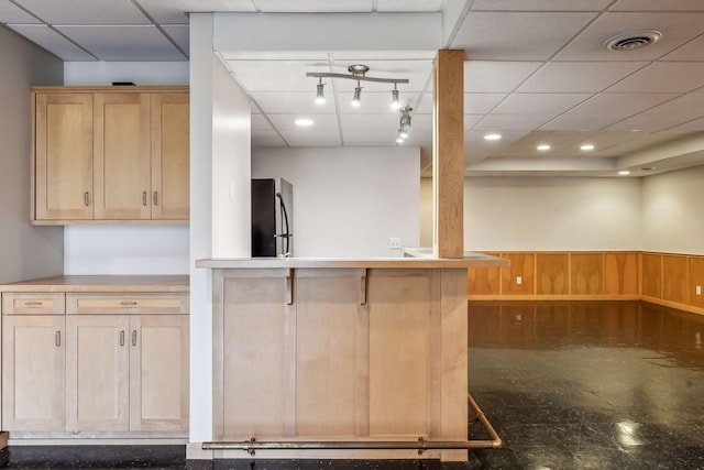 kitchen with a paneled ceiling, light brown cabinets, wooden walls, kitchen peninsula, and stainless steel refrigerator