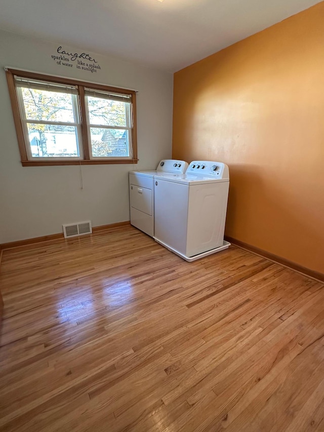 washroom featuring a healthy amount of sunlight, light wood-type flooring, and washing machine and clothes dryer