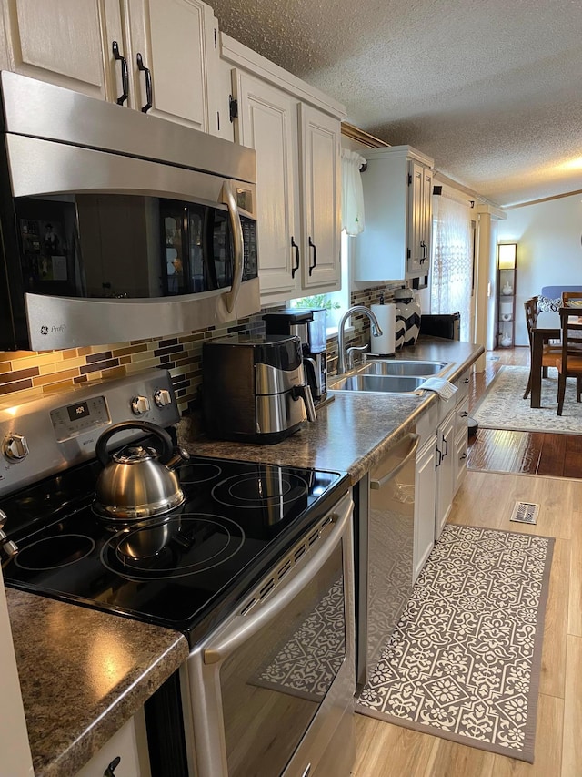 kitchen with light hardwood / wood-style flooring, white cabinets, stainless steel appliances, and sink