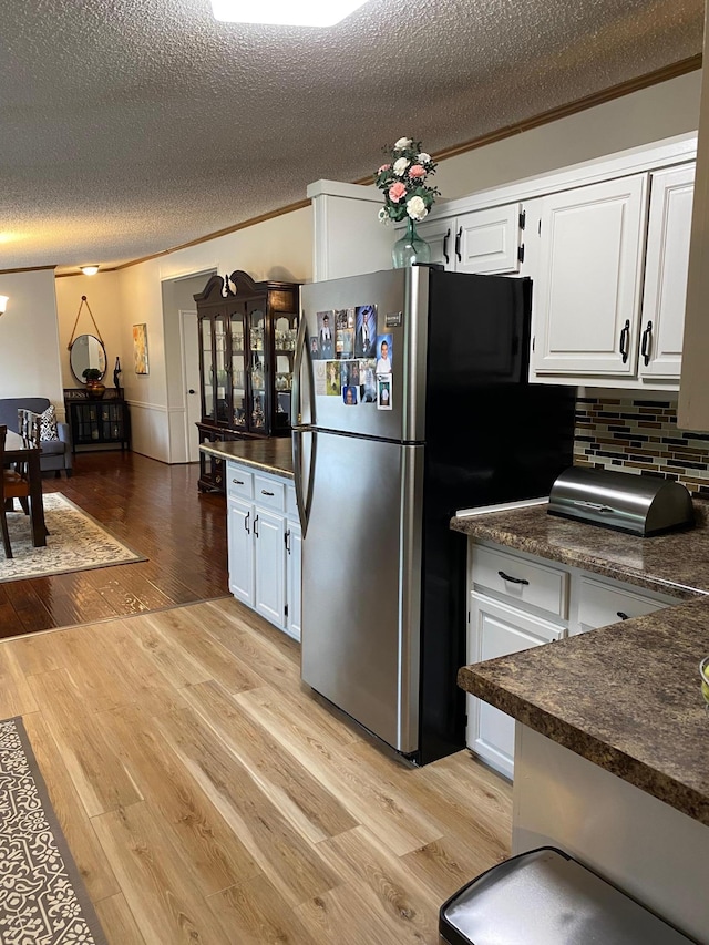 kitchen with white cabinetry, tasteful backsplash, light wood-type flooring, and stainless steel fridge