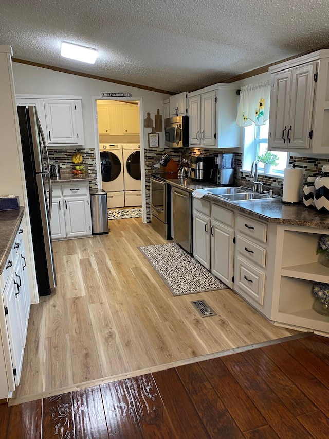 kitchen featuring light wood-type flooring, white cabinets, stainless steel appliances, and separate washer and dryer