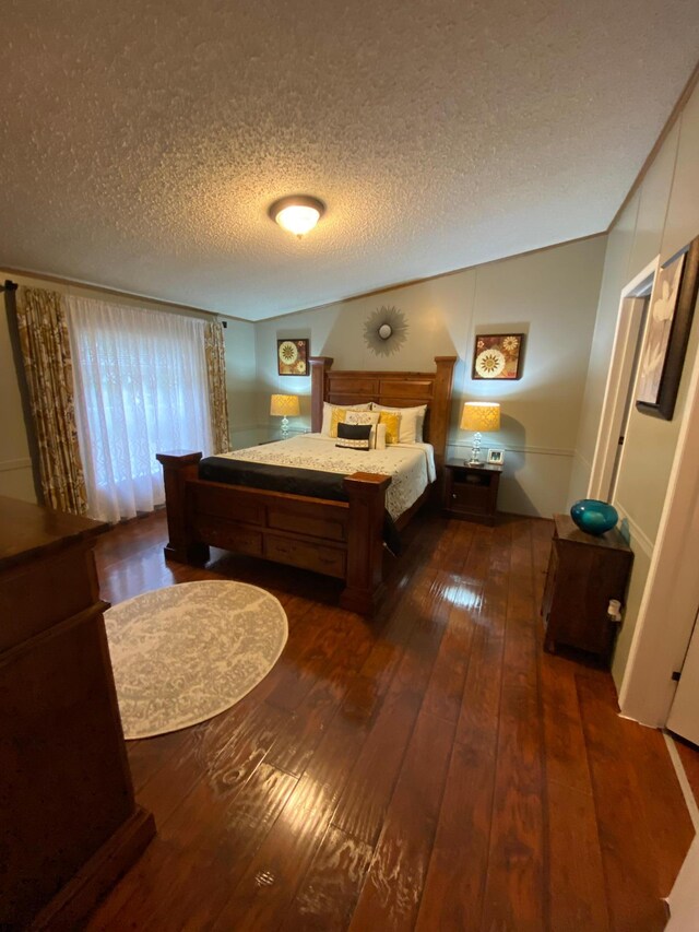 bedroom with a textured ceiling and dark hardwood / wood-style floors