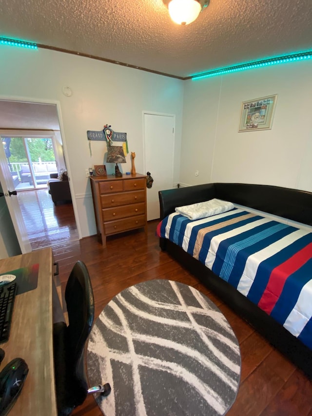 bedroom with dark wood-type flooring, a textured ceiling, and access to outside