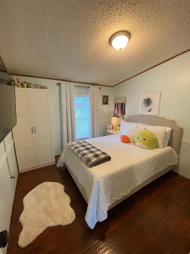 bedroom with crown molding, a textured ceiling, and dark wood-type flooring