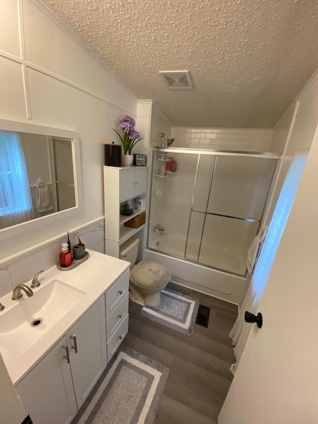 bathroom featuring wood-type flooring, vaulted ceiling, bath / shower combo with glass door, vanity, and a textured ceiling