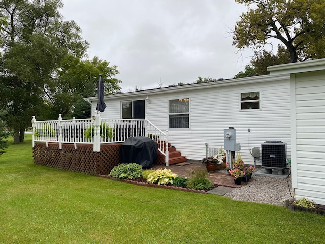 back of property with a wooden deck, a lawn, and central air condition unit