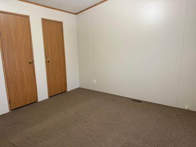 unfurnished bedroom with carpet flooring, a textured ceiling, and ornamental molding