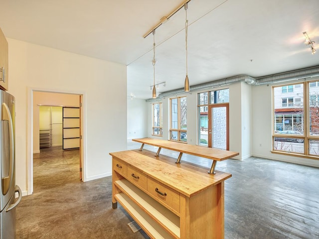 kitchen with butcher block counters, stainless steel refrigerator, pendant lighting, and a kitchen island