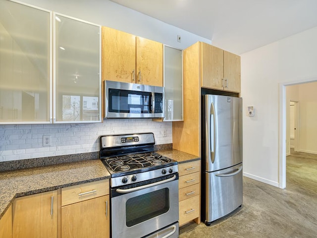 kitchen featuring tasteful backsplash, stainless steel appliances, and dark stone counters