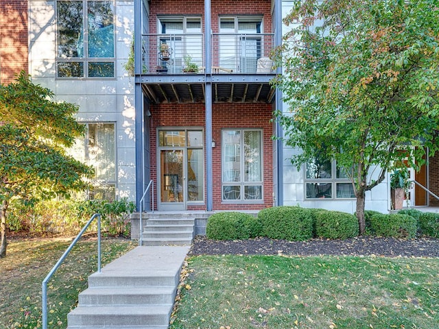 property entrance featuring a yard and a balcony