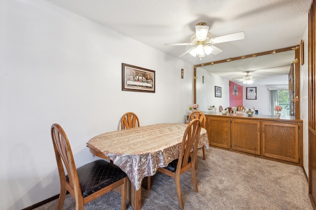 dining space with ceiling fan, light carpet, and a textured ceiling