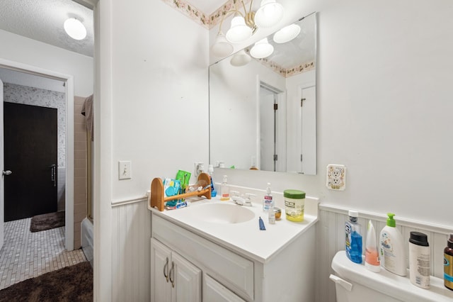 full bathroom featuring toilet, tile patterned flooring, tiled shower / bath combo, vanity, and a textured ceiling