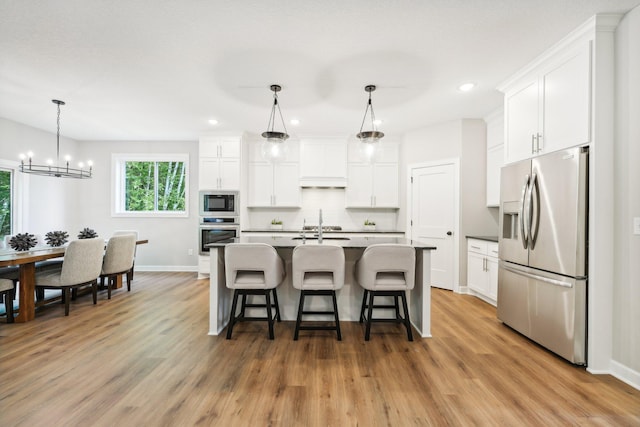 kitchen featuring a center island with sink, appliances with stainless steel finishes, white cabinetry, and light hardwood / wood-style floors