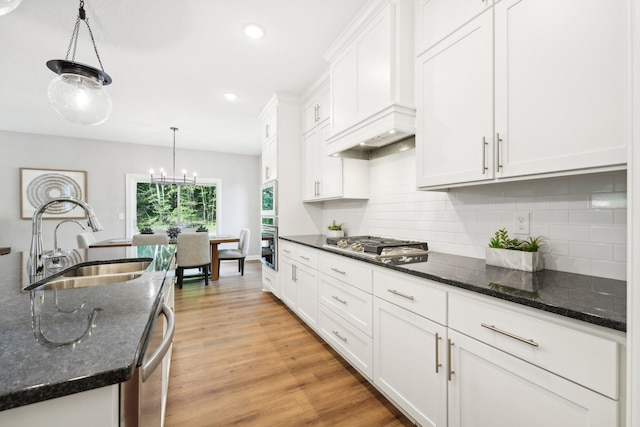 kitchen with light hardwood / wood-style flooring, appliances with stainless steel finishes, sink, and dark stone counters