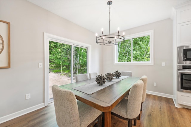 dining area with a healthy amount of sunlight, a chandelier, and dark hardwood / wood-style flooring