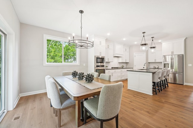 dining area with light hardwood / wood-style floors, a notable chandelier, and sink