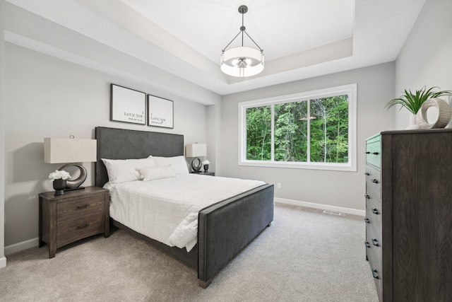 carpeted bedroom with a chandelier and a tray ceiling