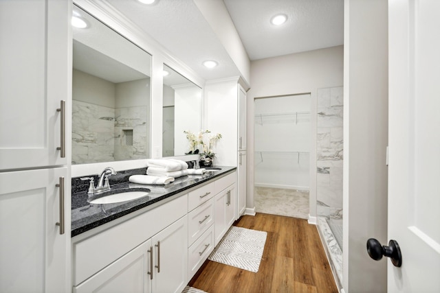 bathroom featuring vanity, a textured ceiling, wood-type flooring, and tiled shower