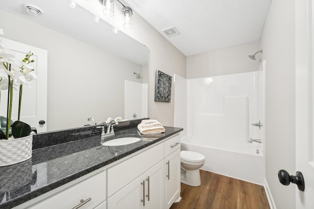 full bathroom featuring toilet, shower / bath combination, hardwood / wood-style floors, vanity, and a textured ceiling