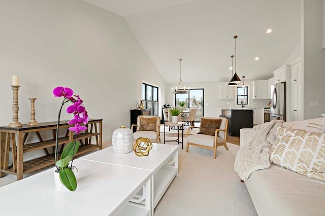 interior space featuring light carpet, sink, high vaulted ceiling, and an inviting chandelier