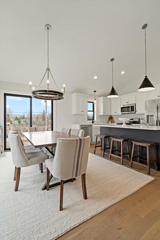 dining room with light hardwood / wood-style floors, a wealth of natural light, and a notable chandelier