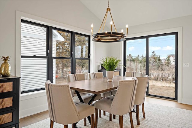 dining room with a chandelier, light hardwood / wood-style floors, and lofted ceiling