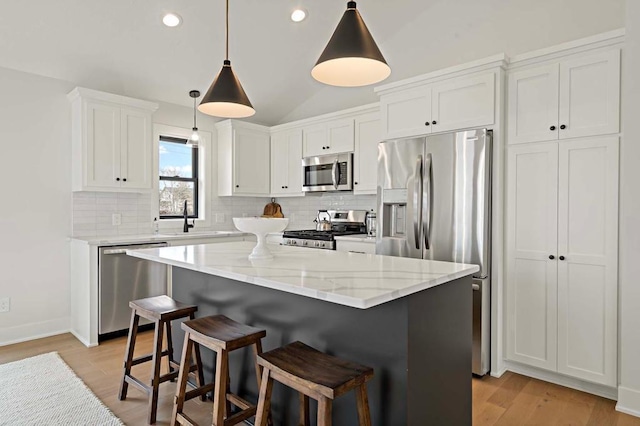 kitchen with appliances with stainless steel finishes, sink, decorative light fixtures, a center island, and white cabinetry