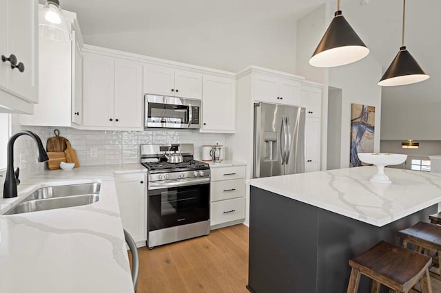 kitchen featuring appliances with stainless steel finishes, sink, decorative light fixtures, white cabinets, and a kitchen island