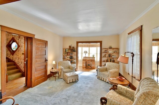 living area featuring crown molding, carpet flooring, baseboards, and stairway
